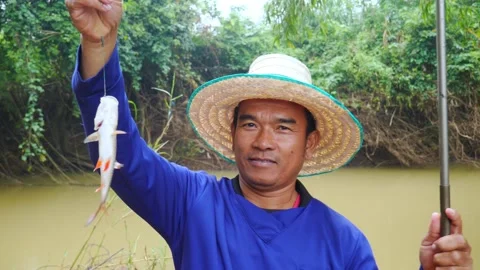A middle-aged Asian man, using a basic fishing rod, Video stock 219413383