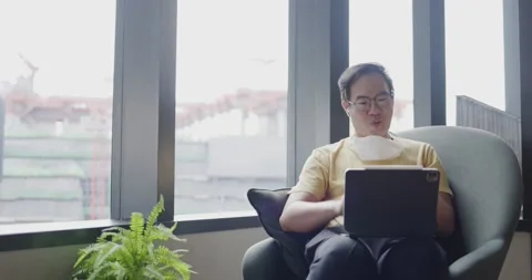 Middle-aged Asian man wearing glasses, face mask spraying alcohol to clean hands Stock Footage 157464289