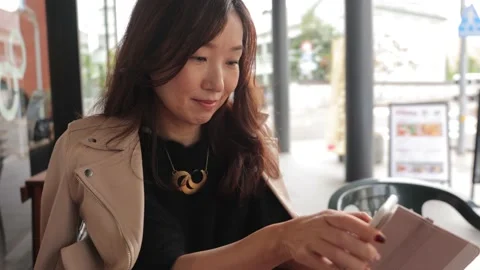 Middle aged asian woman using smartphone at the cafe outside. Stock Footage 224448528