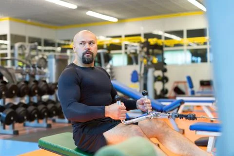 Middle aged athlete doing workouts on a back with power exercise machine in a Foto stock