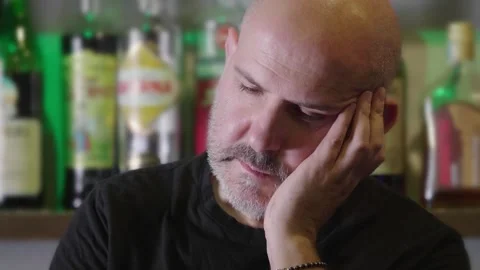 Middle-aged bald man looking sad and downcast in pub Stock Footage 278163713