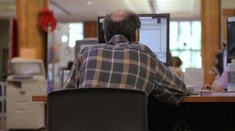 MIDDLE AGED BALDING MAN USING LIBRARY COMPUTER Stock Footage 41663415