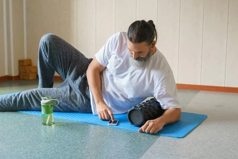 Middle-aged bearded man browsing social media on smartphone after using foam Stock Photos