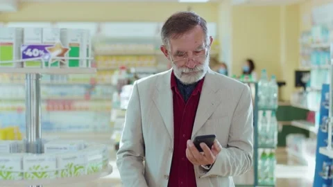 Middle-aged bearded man in glasses looking at medication in the pharmacy use Stock Footage 140764286