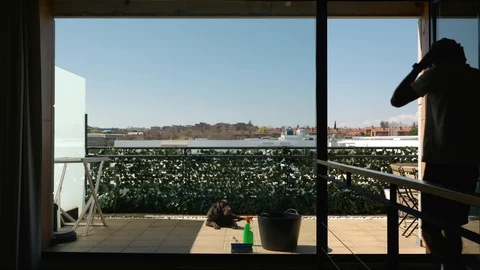Middle-aged bearded man with his dog cleaning the windows of the terrace seen Stock Footage 127832411