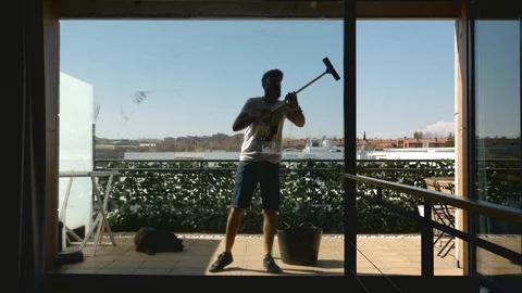 Middle-aged bearded man with his dog cleaning the windows of the terrace seen Stock Footage 127832444