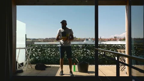 Middle-aged bearded man with his dog cleaning the windows of the terrace seen Stock Footage 127832551