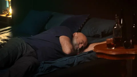 Middle-aged bearded man naps on bed after drinking liquor, alcoholism Stock Footage 346714365
