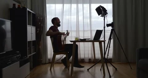 Middle-aged bearded man recording a video of himself playing the guitar in hi Stock Footage 160401241