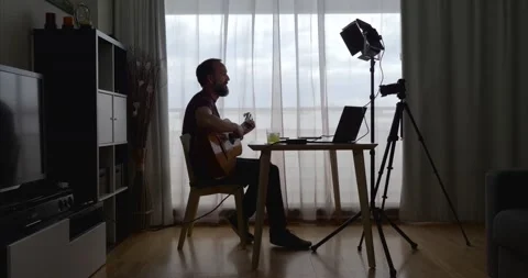 Middle-aged bearded man recording a video of himself playing the guitar in hi Stock Footage 160680310