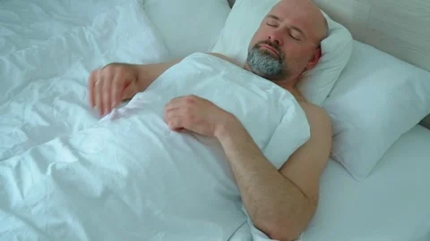 Middle aged bearded man sleeping in morning. Resting male turning to side on bed Stock Footage 309327590