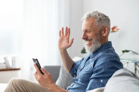 Middle aged bearded man using smartphone for video call Stock Photos