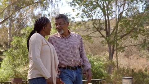 Middle aged black couple laugh while walking in countryside Stock Footage