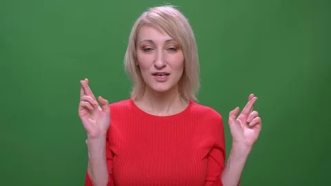 Middle-aged blonde short-haired model prays with crossed fingers isolated on Video stock 108679026