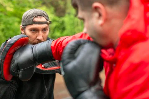 Middle-aged boxer man training with coach outdoors Stock Photos