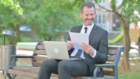 Middle Aged Businessman Celebrating with Documents and Laptop Outdoor Stock Footage 287927336