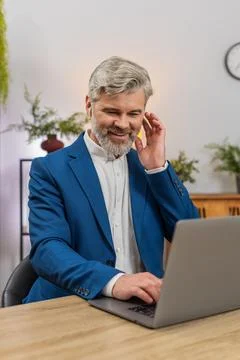 Middle-aged businessman coding on laptop with earphones listens to music focused 스톡 사진