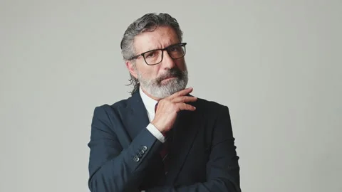 Middle aged businessman hand props chin and looking at camera, isolated on gray Stock Footage 255963381
