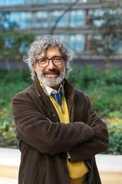 Middle-aged businessman smiling while posing with his arms crossed outdoors at Stock Photos