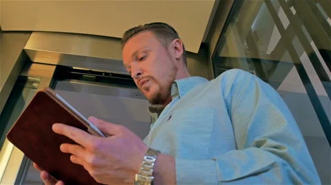 Middle-aged businessman with a tablet computer down in the elevator Stock Footage 49967987