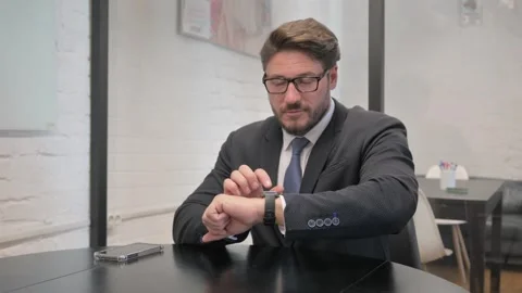 Middle Aged Businessman Using Smart Watch at Workspace Stock Footage 310165363