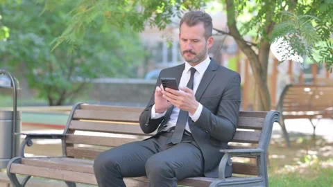 Middle Aged Businessman Using Smartphone while Sitting Outdoor Stock Footage 287923044