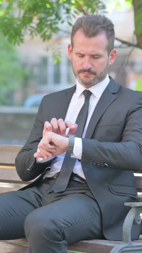 Middle Aged Businessman Using Smartwatch while Sitting Outdoor, Vertical Video Stock Footage 319043115