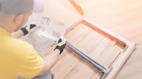 A middle-aged Caucasian man is assembling furniture on the floor using a sc.. Stock Photos