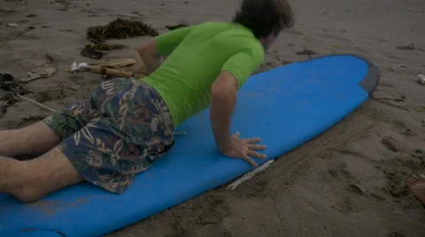 A middle aged caucasian man learns how to get up on a surf board Stock Footage 58932341