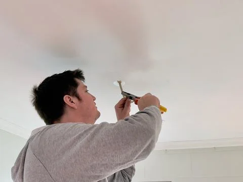 Middle-aged caucasian man using electrical pliers to strip the insulation from c Stock Photos