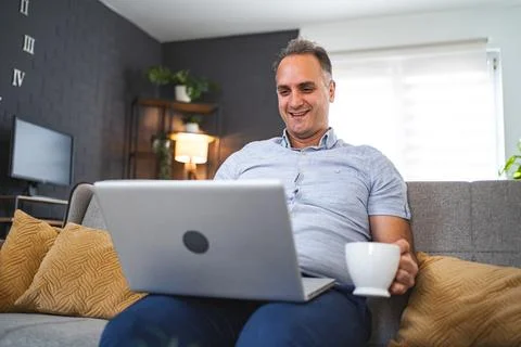Middle aged Caucasian man using laptop on the sofa Stock Photos
