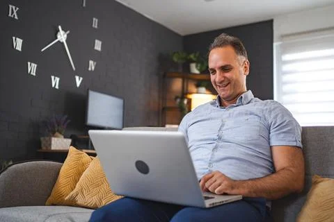Middle aged Caucasian man using laptop on the sofa Stock Photos