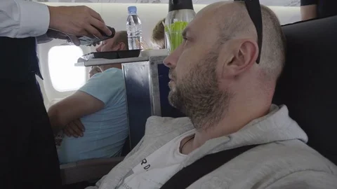 Middle-aged caucasian type man buying a bottle of water in the cabin of airplane Stock Footage 81068721