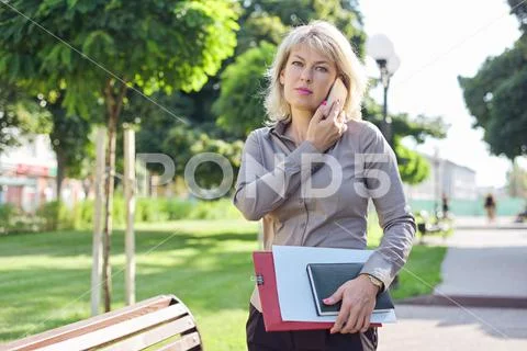 Middle-aged confident business woman talking on smartphone Stock Photos