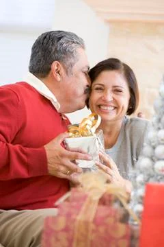 Middle Aged Couple Affectionately Sitting And Holding Christmas Present Stock Photos