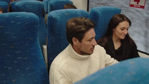 A middle-aged couple are talking and smiling in a train carriage. a man takes Stock Footage 199519611