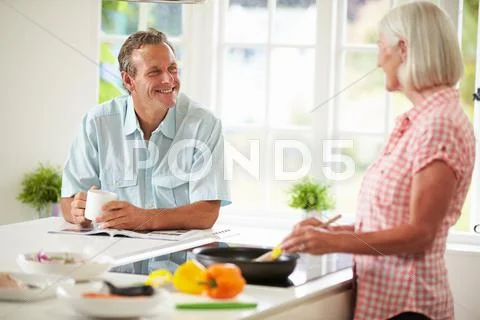 Middle aged couple cooking meal in kitchen together Stock Photos