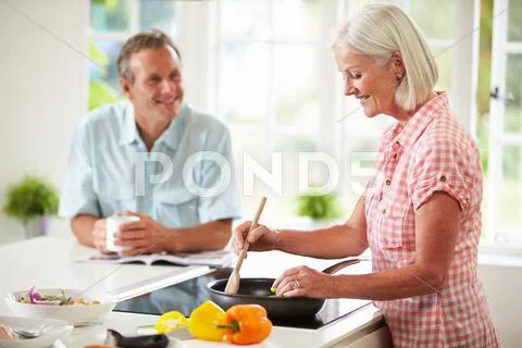 Middle aged couple cooking meal in kitchen together Stock Photos