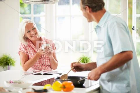 Middle aged couple cooking meal in kitchen together Stock Photos