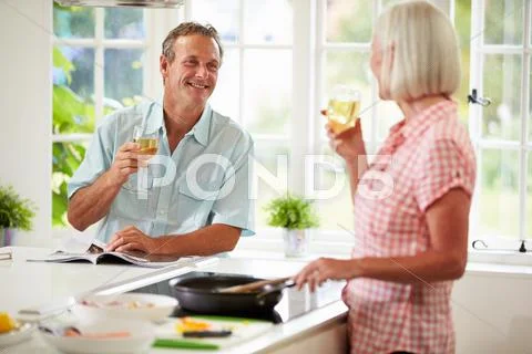 Middle aged couple cooking meal in kitchen together Stock Photos