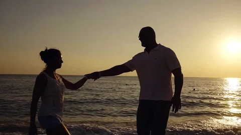 Middle-aged couple is dancing in a sunset time on a beach near sea, old wooden Stock Footage 81721152