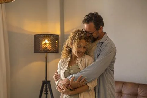 Middle-aged couple embracing lovingly at home in a cozy living room with wa.. Fotos de archivo