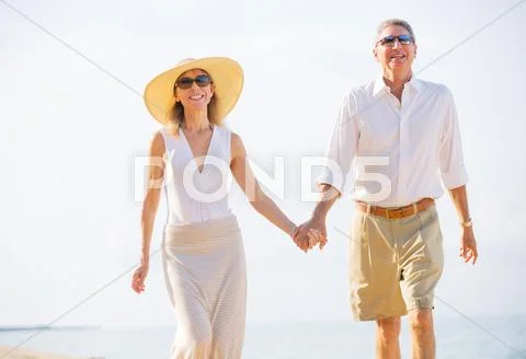Middle aged couple enjoying walk on the beach Stock-Fotos
