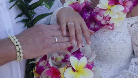 Middle aged couple hold wedding rings above floral plumeria bouquet. Stock Footage 135236374