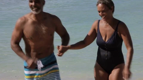 Middle-aged couple holding hands on a beach. 스톡 동영상 88367817