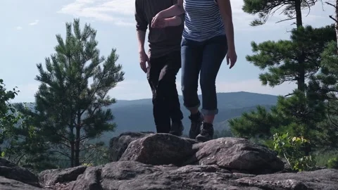 Middle-aged couple, holding hands, descends from the mountain. Sunny summer day. Stock Footage 170143989