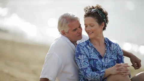 Middle-aged couple laughing on a beach. 스톡 동영상 88370620