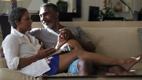 Middle-aged couple laughing on a sofa. 스톡 동영상 88367413