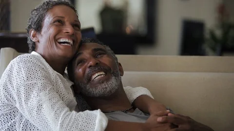 Middle-aged couple laughing on a sofa. 스톡 동영상 88367426