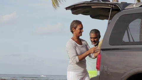 Middle-aged couple loading a car by the sea. 스톡 동영상 88370858